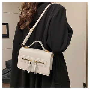 Close-up of white leather square bag with double gold zippers and tassel on black suit