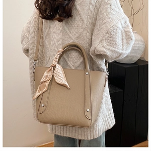Détail d'un sac seau en cuir kaki avec foulard et bandoulière réglable porté par mannequin