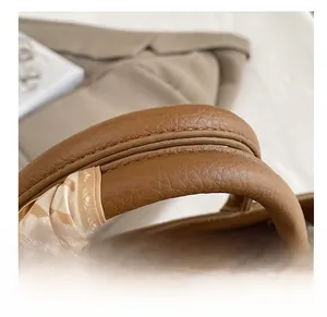 Gros plan du sac seau en cuir marron avec foulard en soie élégant sur la poignée