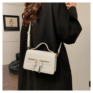 Detail of white leather crossbody bag with dual zipper design and gold metal hardware