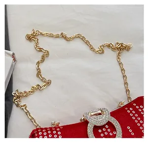 Detail of red velvet evening bag with rhinestone buckle and gold chain strap