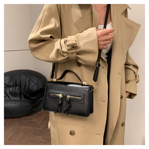 Detail of a black leather shoulder bag with double zippers and golden metal hardware