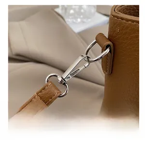 Gros plan du crochet rotatif en métal argenté et cuir grainé de ce sac seau marron