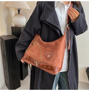 Detail of vintage brown suede tote bag featuring decorative zippers and metal eyelets