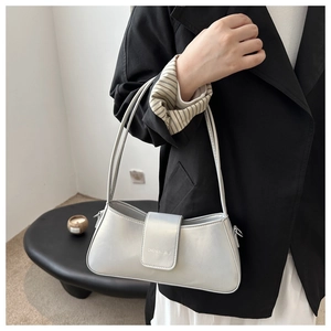 Detailed side view of a metallic silver baguette bag with engraved strap on black suit