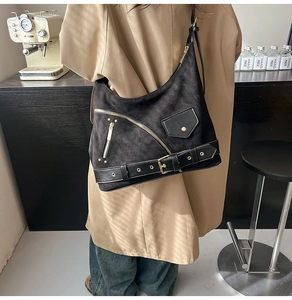 Close-up of black suede motorcycle tote bag with golden zippers and buckle details