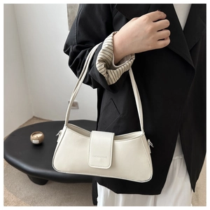 Detail of cream baguette bag showing refined leather texture and embossed brand logo