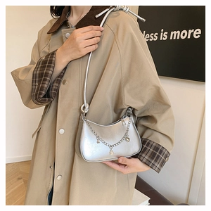 Détail du sac à main argenté métallisé avec charms perle, étoile et cœur sur la chaîne