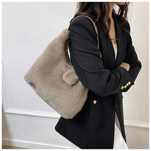 Détail d'un sac à main en peluche kaki avec étiquette violette porté par un mannequin