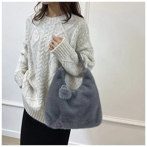 Détail du sac à bandoulière en peluche grise avec étiquette décorative violette
