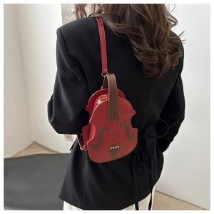 Detail view of a vintage dark red violin-shaped shoulder bag on a black blazer