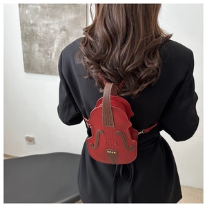 Detailed back view of a red violin-shaped crossbody bag worn over a black blazer
