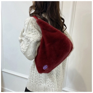 Détail de la texture d'un sac à main triangulaire en fausse fourrure bordeaux