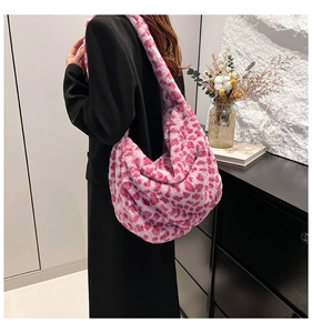Detailed texture of pink leopard print plush hobo bag on model in black suit