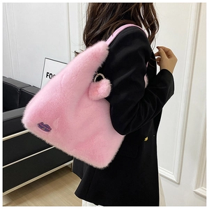 Détail du sac fourre-tout en fausse fourrure rose avec pompon et étiquette de mode