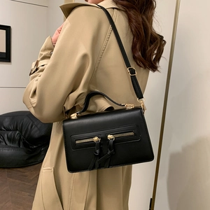 Retro black crossbody bag with double zipper detail shown on a khaki trench coat