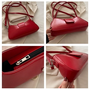 Detail view of red glossy leather baguette bag featuring metal zipper and magnetic flap closure