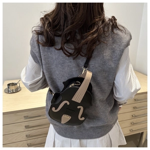 Detailed back view of a person wearing a unique violin shaped crossbody bag in beige and black