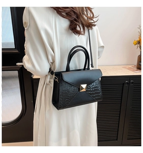 Detail of black faux leather tote with crocodile pattern and gold square buckle on a model