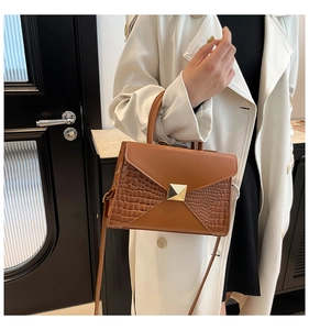 Detailed view of the brown envelope flap handbag with crocodile texture and gold clasp