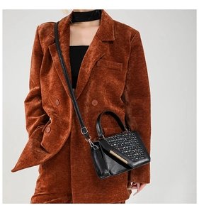 Dettaglio del patchwork in tweed e pelle su borsa a tracolla con finiture in metallo oro