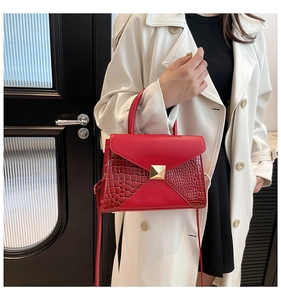 Detail of red crocodile texture paneling and gold square buckle on a stylish tote bag