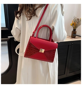 Detail of red crocodile pattern patchwork bag with golden stud and round handle