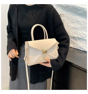 Detail of cream crocodile embossed handbag with gold buckle and adjustable strap