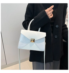 Detail showing the white crocodile pattern patchwork and golden pyramid clasp on the handbag
