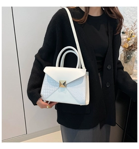 Detail of white crocodile texture leather handbag with golden geometric turn-lock buckle