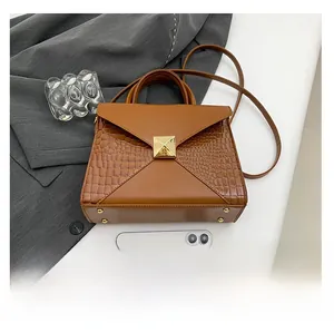 Detailed view of brown PU leather crossbody bag with crocodile texture and phone for scale