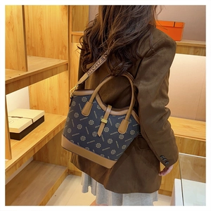 Détail du sac seau vintage avec imprimé floral bleu marine et garniture en cuir brun