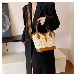 Détail du sac en toile avec logo, finitions en cuir et bandoulière en tissu griffée