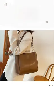 Brown leather tote bag featuring metal chain shoulder straps and a spacious square design