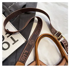 Détail d'un sac en cuir marron vintage avec large bandoulière jacquard et boucle dorée
