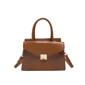 Brown crocodile pattern patchwork tote bag with gold pyramid hardware on white background