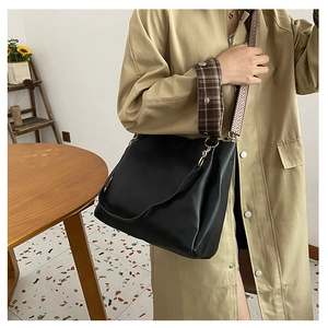 Detail of black tote bag with bohemian geometric woven strap on a trench coat