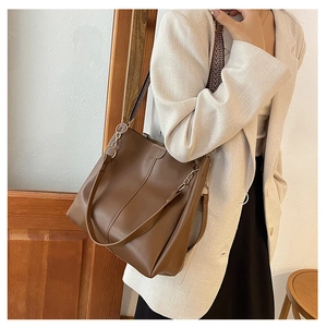 Detail of coffee tote bag featuring metallic chain buckle and woven shoulder strap texture