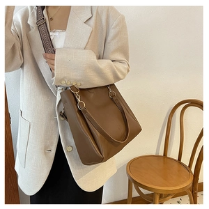 Detail showing brown leather tote bag with stylish patterned strap and gold metal rings