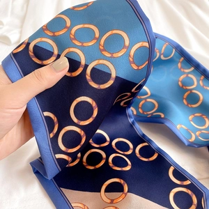 Nahaufnahme eines schmalen Seidenschals mit blauen geometrischen Mustern und Satin-Textur