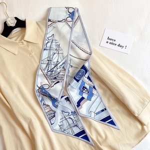 Détail d'un foulard twilly à imprimé nautique porté sur une chemise beige à ancres