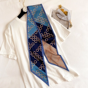 Detail eines seidigen schmalen Schals mit blauem Blockmuster und goldener Kette