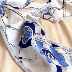 Détail d'un foulard en soie nautique avec motifs ancre et corde sur tissu beige