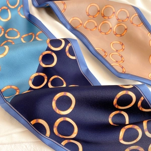 Nahaufnahme eines eleganten Seidenschals mit marineblauen und champagnerfarbenen Ringen