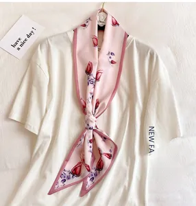Detail of floral skinny scarf with red roses on pink silk fabric knotted on white tee
