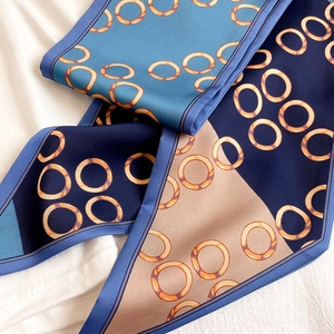 Detailansicht eines schmalen Seidenschals mit blauem und orangefarbenem Muster