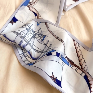Détail d'un foulard Twilly à motif nautique avec voiliers et cordages sur fond beige