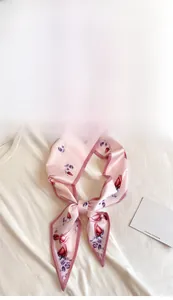 Close-up of pink silk scarf with red tulip floral pattern worn on a white t-shirt neckline