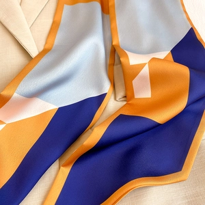 Detail eines Seidenschals mit geometrischem Muster auf einem Leinenblazer in Beige