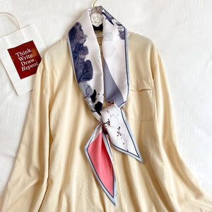 Détail d'un foulard étroit et soyeux à motifs floraux noué sur un col de chemise